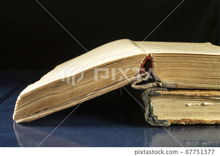 Aging book rests upon glass table with reflection 87751377
