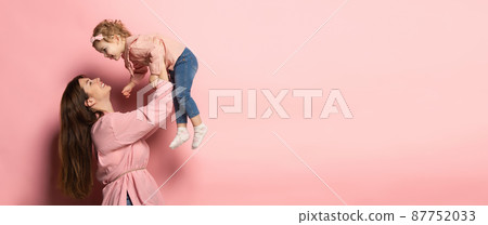 Play. Portrait of young woman and little girl, mother and daughter isolated on pink studio background. Mother's Day celebration. Concept of family, childhood, motherhood 87752033