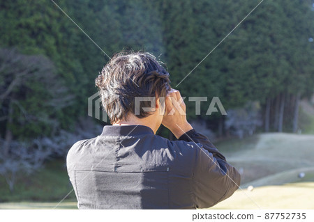 A man measuring a distance at a golf course 87752735