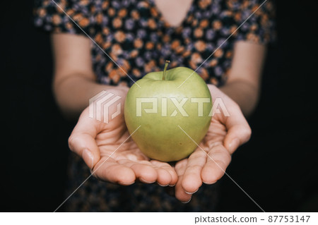 green apple in hands of woman 87753147