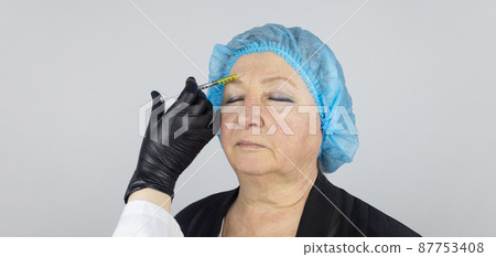 Botulinum toxin injection. Senior woman at the appointment with a beautician who is preparing to give anti-wrinkle injections. Loose skin and hypotension. Mimic wrinkles and contouring Botulinum toxin injection. Senior woman at the appointment with a beautician who is preparing to give anti-wrinkle injections. Loose skin and hypotension. Mimic wrinkles and contouring 87753408