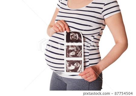 Pregnant woman standing and holding her ultrasound baby scan 87754504