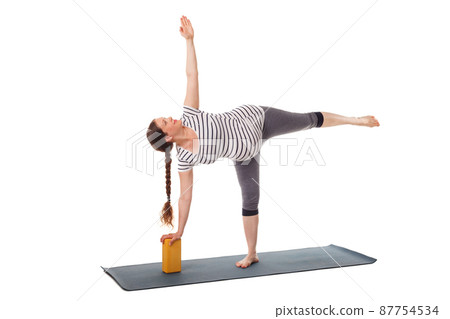 Pregnant woman doing yoga asana Virabhadrasana 1 87754534