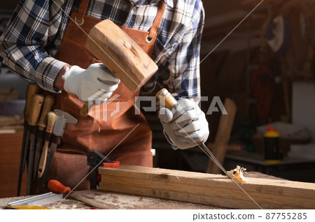 Skilled carpenter carving wood with hammer and chisel 87755285