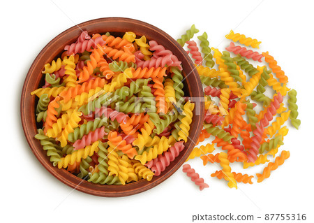 raw Fusilli colored pasta in ceramic bowl isolated on white background with clipping path and full depth of field. Top view. Flat lay 87755316