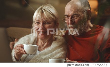 Senior couple with tea watching movie together Senior couple with tea watching movie together 87755564