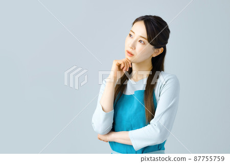 A young housewife in an apron thinking A young housewife in an apron thinking 87755759