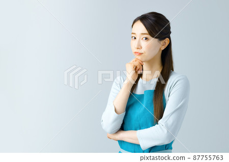 A young housewife in an apron thinking A young housewife in an apron thinking 87755763