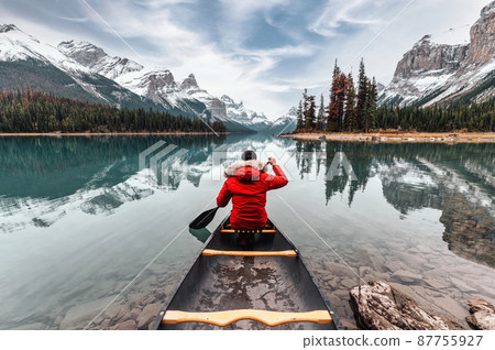 Male traveler in winter coat canoeing in Spirit Island on Maligne Lake at Jasper national park Male traveler in winter coat canoeing in Spirit Island on Maligne Lake at Jasper national park 87755927