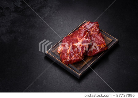 Raw organic marbled beef steaks with spices on a wooden cutting board Raw organic marbled beef steaks with spices on a wooden cutting board 87757096