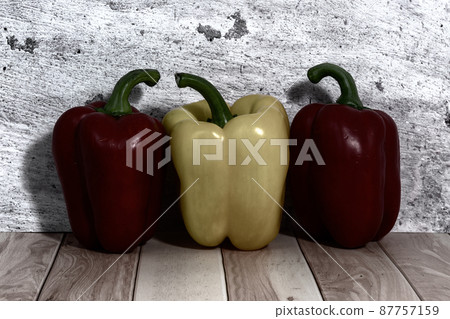 Large sweet peppers stand in a row on a table near wall Large sweet peppers stand in a row on a table near wall 87757159
