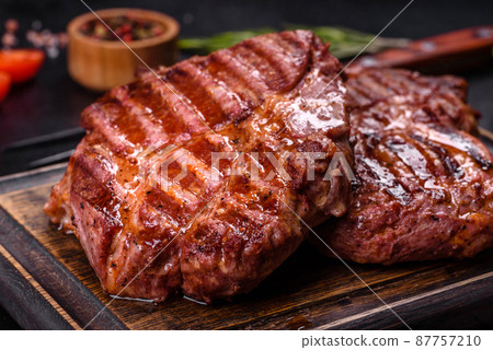 Grilled ribeye beef steak, herbs and spices on a dark table Grilled ribeye beef steak, herbs and spices on a dark table 87757210