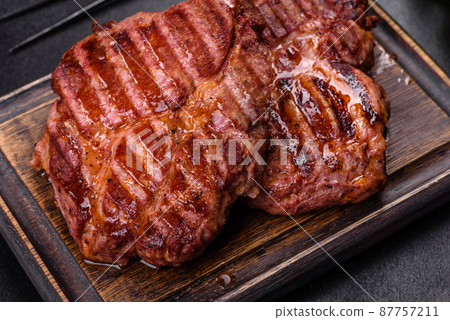 Grilled ribeye beef steak, herbs and spices on a dark table Grilled ribeye beef steak, herbs and spices on a dark table 87757211