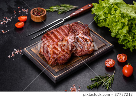 Grilled ribeye beef steak, herbs and spices on a dark table 87757212