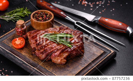 Grilled ribeye beef steak, herbs and spices on a dark table 87757236