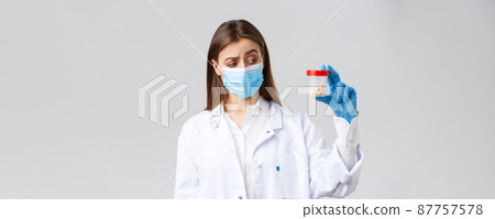 Covid-19, preventing virus, healthcare workers and quarantine concept. Unsure, curious doctor in scrubs and medical mask look intrigued and uncertain at container with medicine pills Covid-19, preventing virus, healthcare workers and quarantine concept. Unsure, curious doctor in scrubs and medical mask look intrigued and uncertain at container with medicine pills 87757578