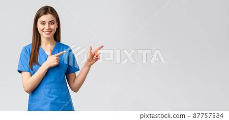 Healthcare workers, prevent virus, insurance and medicine concept. Smiling nurse or female doctor in blue scrubs, pointing fingers down, inform about coronavirus news, show information 87757584