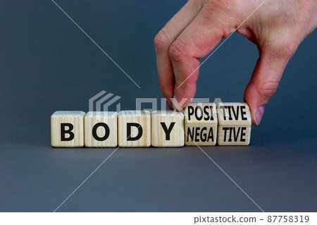 Body positive or negative symbol. Psychologist turns cubes, changes words body negative to body positive. Beautiful grey background, copy space. Psychological, body positive or negative concept. Body positive or negative symbol. Psychologist turns cubes, changes words body negative to body positive. Beautiful grey background, copy space. Psychological, body positive or negative concept. 87758319