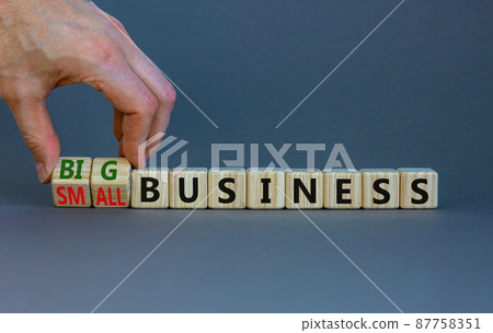 Big or small business symbol. Businessman turns wooden cubes, changes words small business to big business. Beautiful grey background, copy space. Big or small business concept. Big or small business symbol. Businessman turns wooden cubes, changes words small business to big business. Beautiful grey background, copy space. Big or small business concept. 87758351