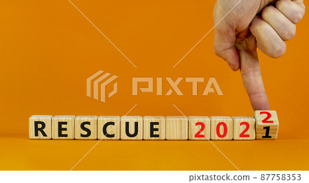 2022 rescue new year symbol. Businessman turns wooden cubes and changes words 'rescue 2021' to 'rescue 2022'. Beautiful orange background, copy space. Business, 2022 rescue new year concept. 87758353