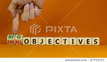 Big or small objectives symbol. Businessman turns wooden cubes, changes words small objectives to big objectives. Beautiful orange background, copy space. Business, big or small objectives concept. 87758354