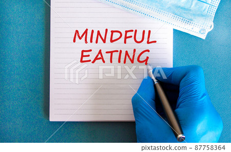 Mindful eating symbol. White note with words Mindful eating, beautiful blue background, doctor hand in blu glove and metallic pen. Medical mask. Medical and mindful eating concept. 87758364
