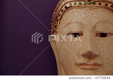 Closeup of buddha face image on dark violet background Closeup of buddha face image on dark violet background 87758648