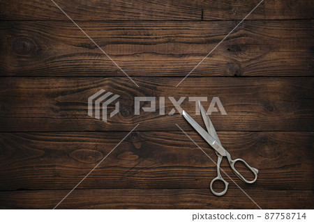 Tailoring scissors on dark wooden table. Copy space for text. Top view. Tailoring scissors on dark wooden table. Copy space for text. Top view. 87758714