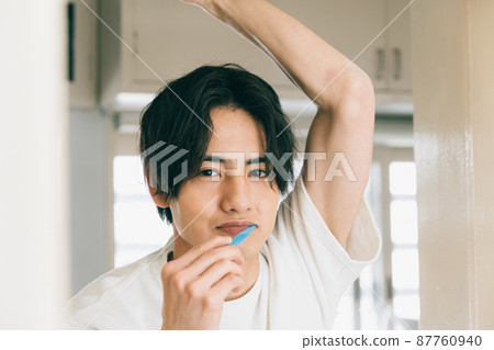 A young man brushing a tooth A young man brushing a tooth 87760940