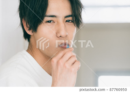 A young man brushing a tooth A young man brushing a tooth 87760950