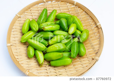 Bilimbi fruit in bamboo basket on white background. 87760972