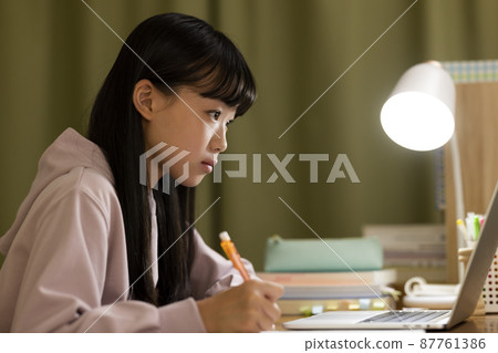 A girl studying while looking at a computer 87761386