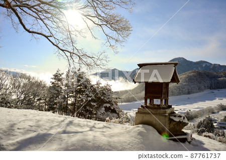 A snowy landscape watched over by a shrine 87761737