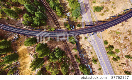 Aerial of train tracks crossing over tracks and road in desert Aerial of train tracks crossing over tracks and road in desert 87762537