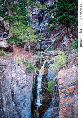 Tiers of very tall waterfalls cutting through canyon gorge in the mountains Tiers of very tall waterfalls cutting through canyon gorge in the mountains 87762643