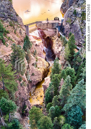 Vertical aerial view of large dam leading to gorge canyon with waterfall Vertical aerial view of large dam leading to gorge canyon with waterfall 87762668