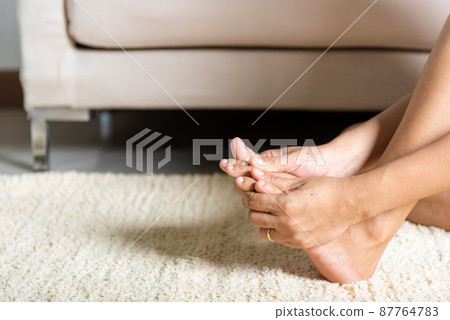 Asian woman holds her toe injury feeling pain her foot at home 87764783