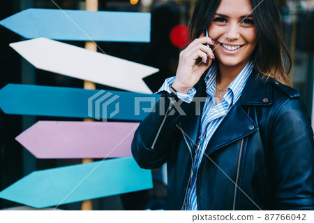 Smiling woman having phone call on street 87766042