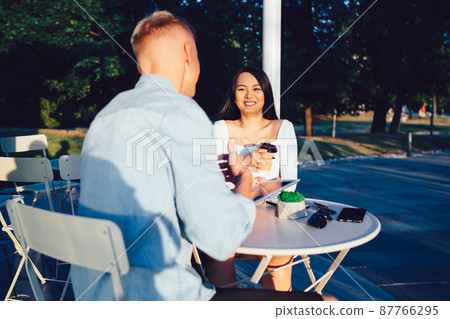 Cheerful diverse couple talking in outdoor cafe Cheerful diverse couple talking in outdoor cafe 87766295