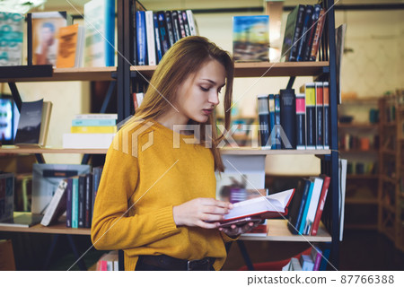Young woman reading book in library 87766388