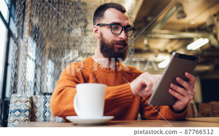 Calm man chilling with tablet in cafe 87766512