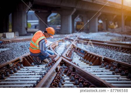 Engineer under discussion inspection and checking construction process railway switch and checking work on railroad station .Engineer wearing safety uniform and safety helmet in work. 87766588
