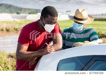 Farmers in masks signing papers near car Farmers in masks signing papers near car 87766598