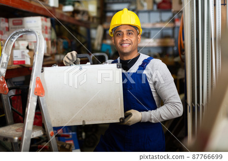 Foreman in protective helmet and overalls with toolbox in hardware store 87766699