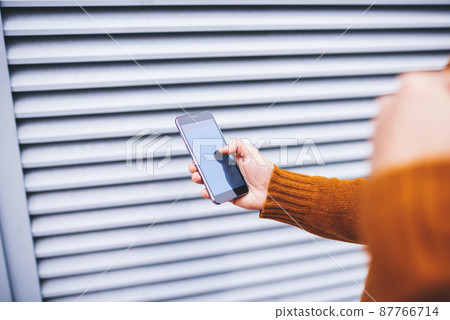 Crop man messaging on phone while walking 87766714