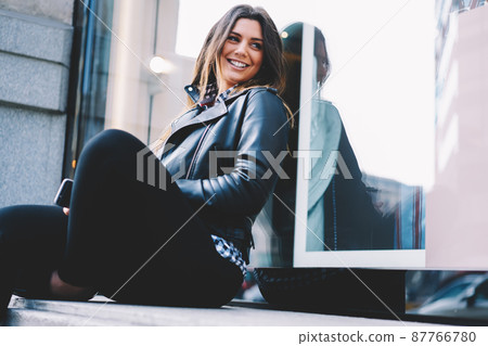 Positive woman sitting near window on street Positive woman sitting near window on street 87766780
