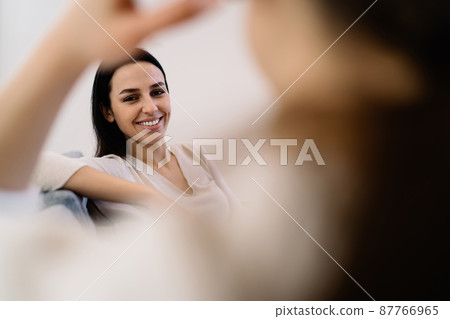Smiling woman looking at camera in light room Smiling woman looking at camera in light room 87766965