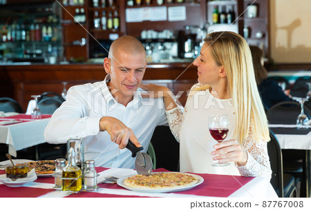 Loving cheerful positive pair enjoying pizza and conversation at restaurant 87767008