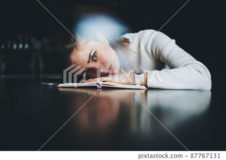 Student lying on table and looking tired doing homework 87767131