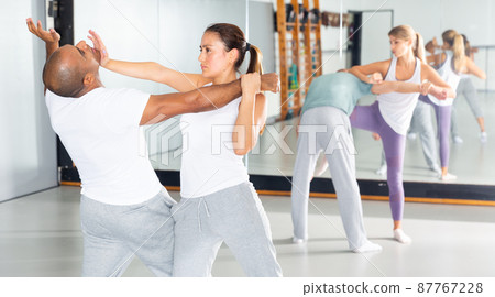 Hispanic girl using palm to launch blow in chin during self defence training 87767228